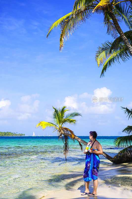 侧面的女人站在沙滩附近的绿松石海在Isla Pelicano岛在加勒比海看到